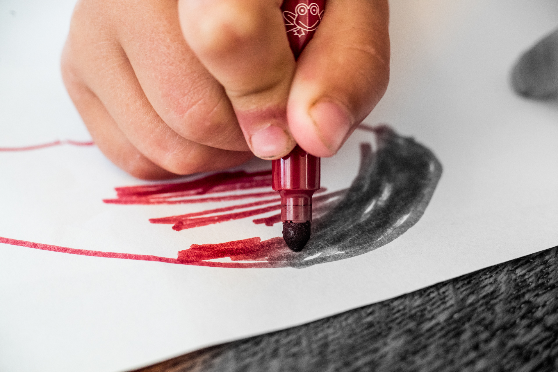 Child hand coloring red to black and white